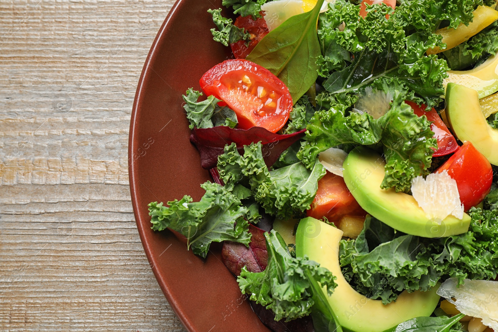 Photo of Tasty fresh kale salad on wooden table, top view