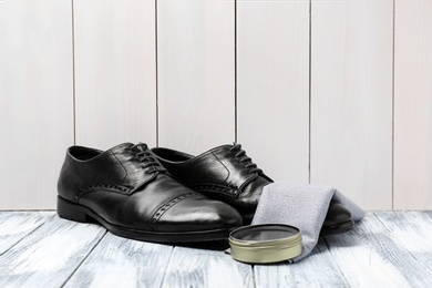 Leather footwear and shoe shine kit on white wooden surface