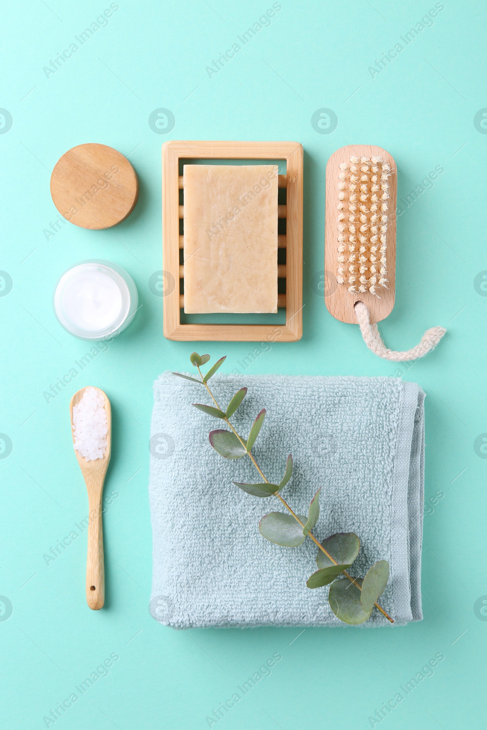 Photo of Jar of cream, body care products and eucalyptus branch on turquoise background, flat lay