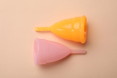 Photo of Menstrual cups on beige background, flat lay