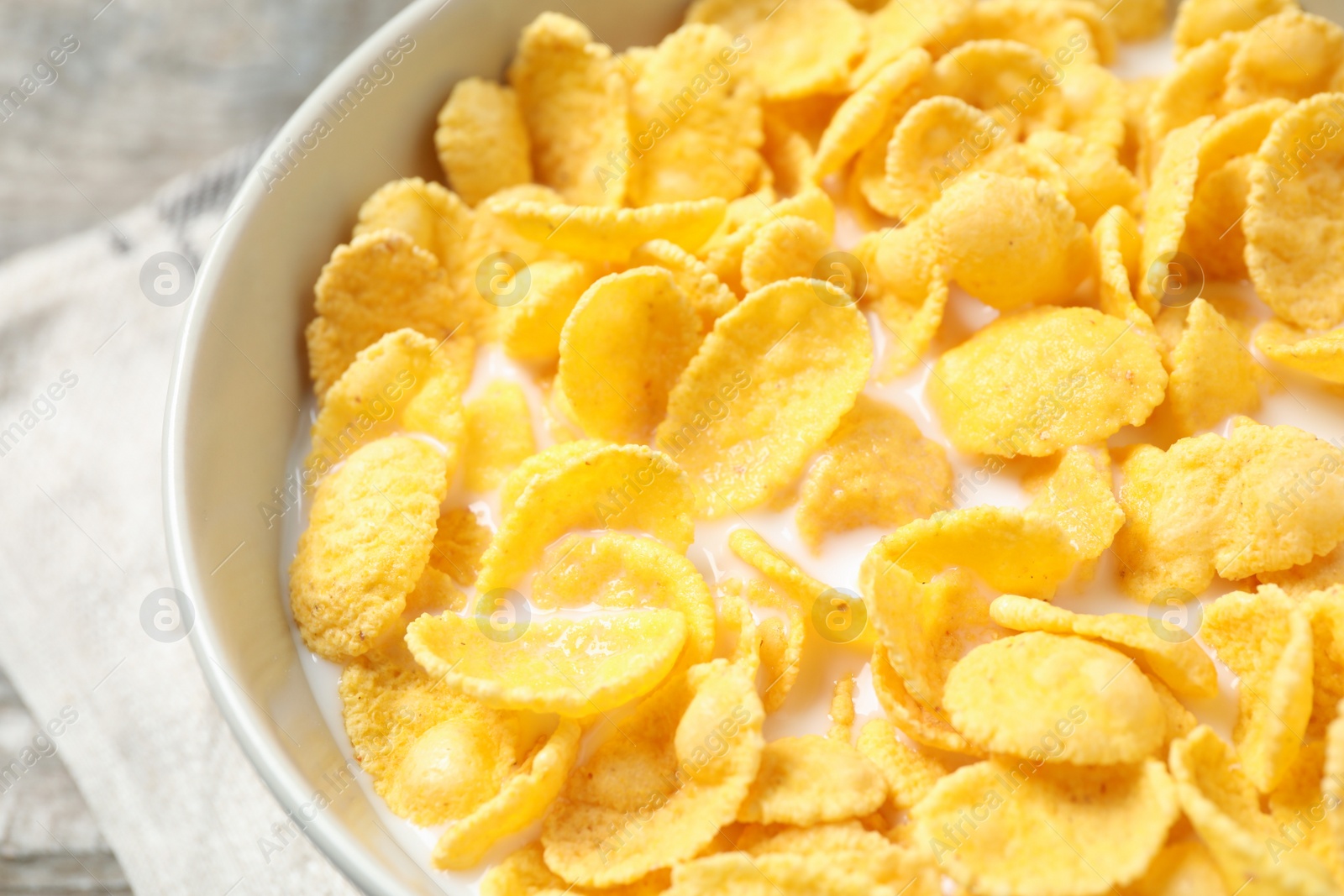 Photo of Tasty crispy corn flakes with milk in bowl, closeup