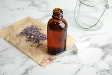 Photo of Natural herbal oil and lavender on marble table