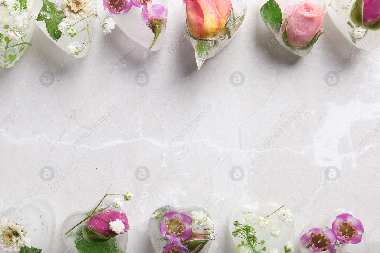 Photo of Frame made of heart shaped floral ice cubes on color background, top view. Space for text