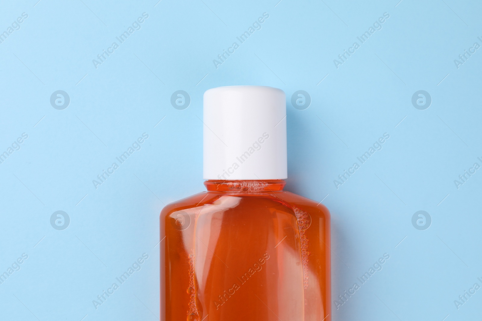 Photo of Fresh mouthwash in bottle on light blue background, top view