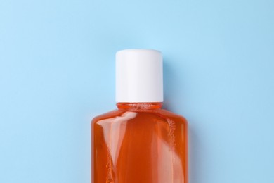 Photo of Fresh mouthwash in bottle on light blue background, top view