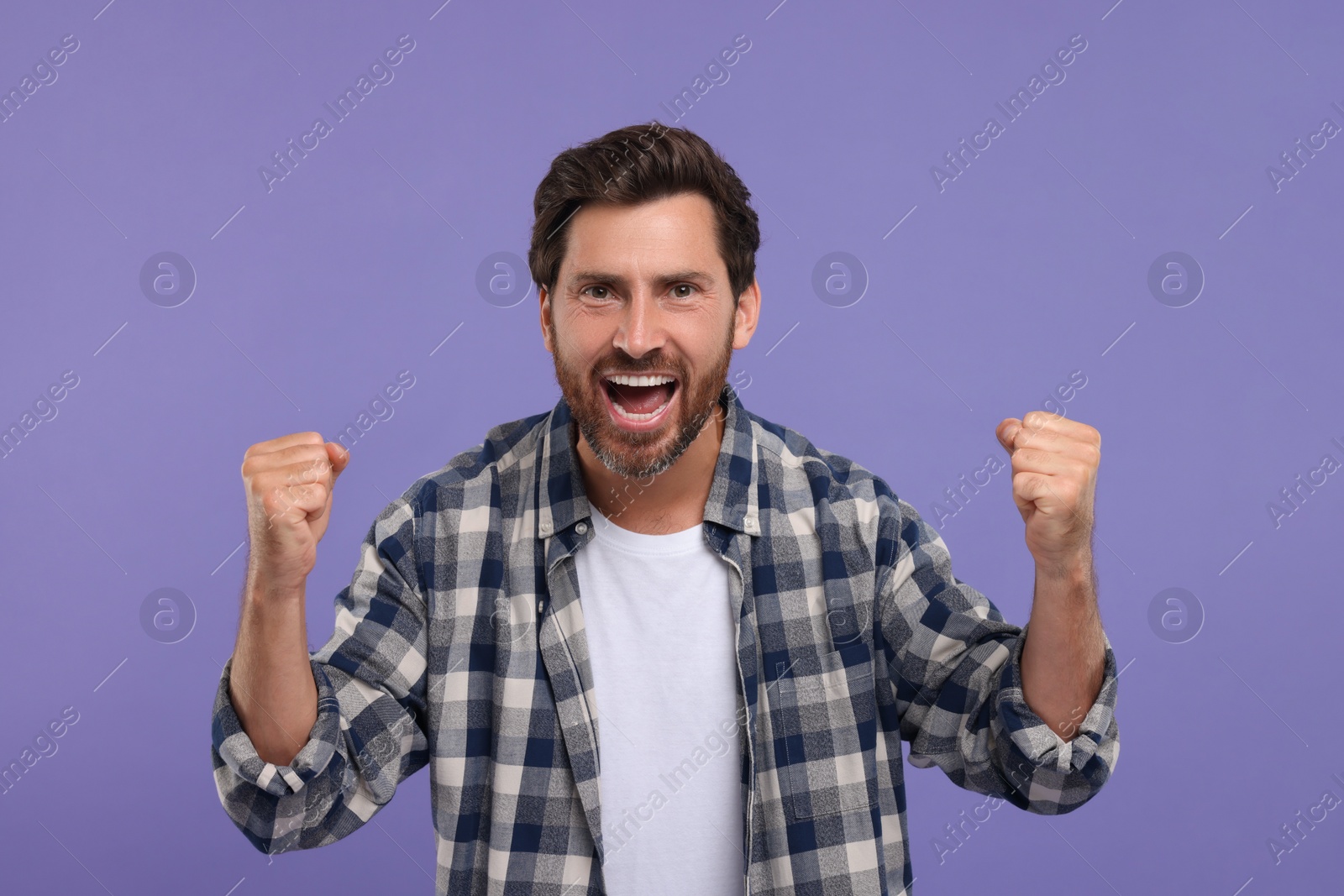 Photo of Emotional sports fan celebrating on purple background