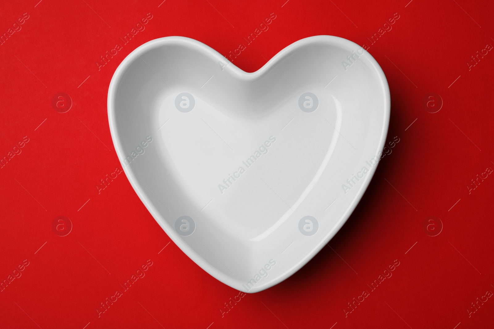 Photo of Heart shaped plate on color background, top view