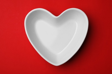 Photo of Heart shaped plate on color background, top view