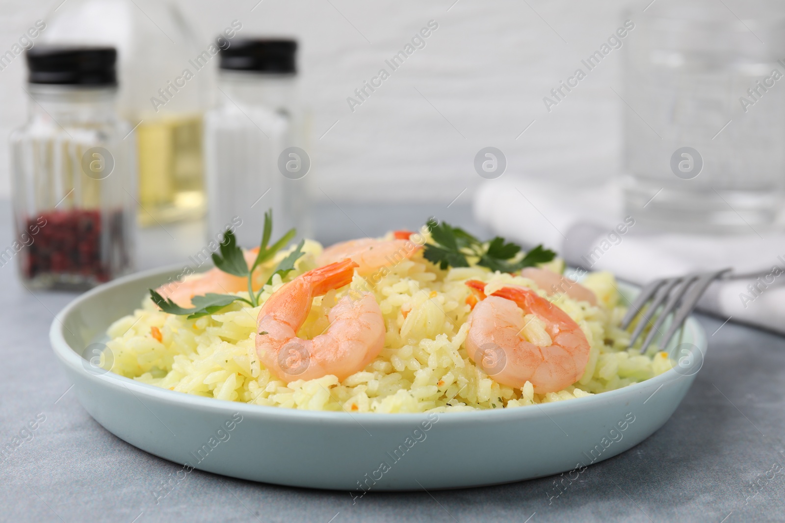 Photo of Delicious risotto with shrimps and parsley on light grey table, closeup