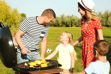 Photo of Happy family with little children having barbecue in park