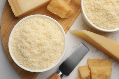 Flat lay composition with whole and grated parmesan cheese on white table