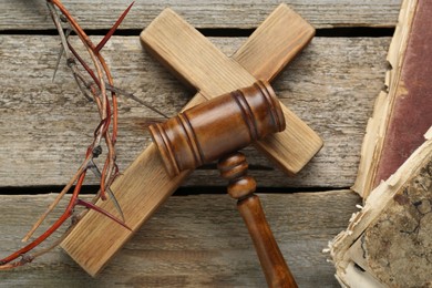 Photo of Judge gavel, cross and crown of thorns on wooden table, flat lay