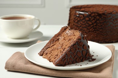Photo of Piece of delicious chocolate truffle cake on white table, closeup