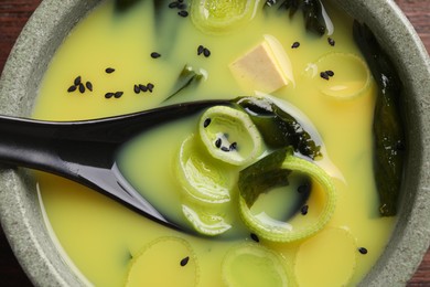 Bowl of delicious miso soup with tofu and spoon, top view