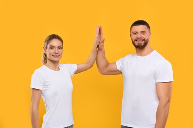 Happy couple giving high five on orange background