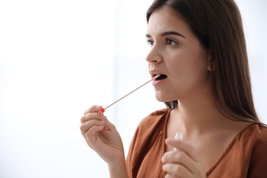 Woman taking sample for DNA test on light background