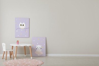 Photo of Children's room interior with table, cute paintings and empty wall. Space for design