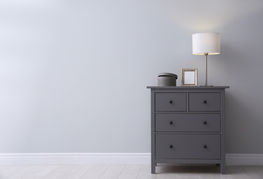 Photo of Modern grey chest of drawers near light wall in room, space for text. Interior design