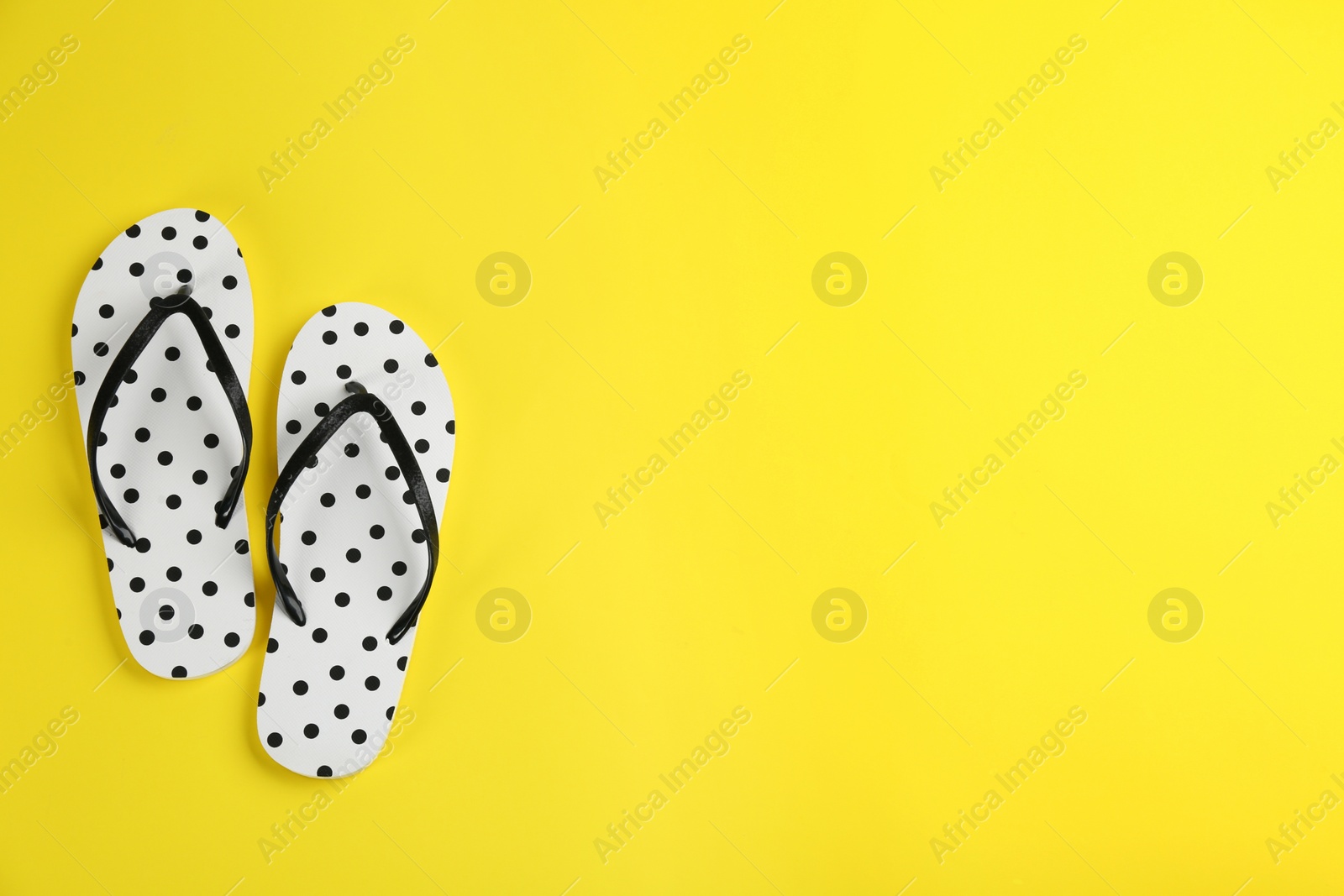 Photo of Stylish flip flops on yellow background, flat lay. Space for text