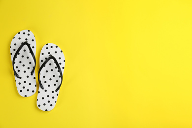 Stylish flip flops on yellow background, flat lay. Space for text