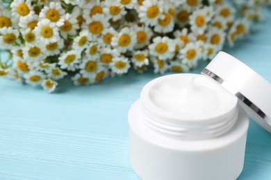 Chamomile flowers and cosmetic product on wooden table, closeup. Space for text