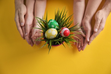 Photo of Family with composition of plant and Easter eggs on color background, top view