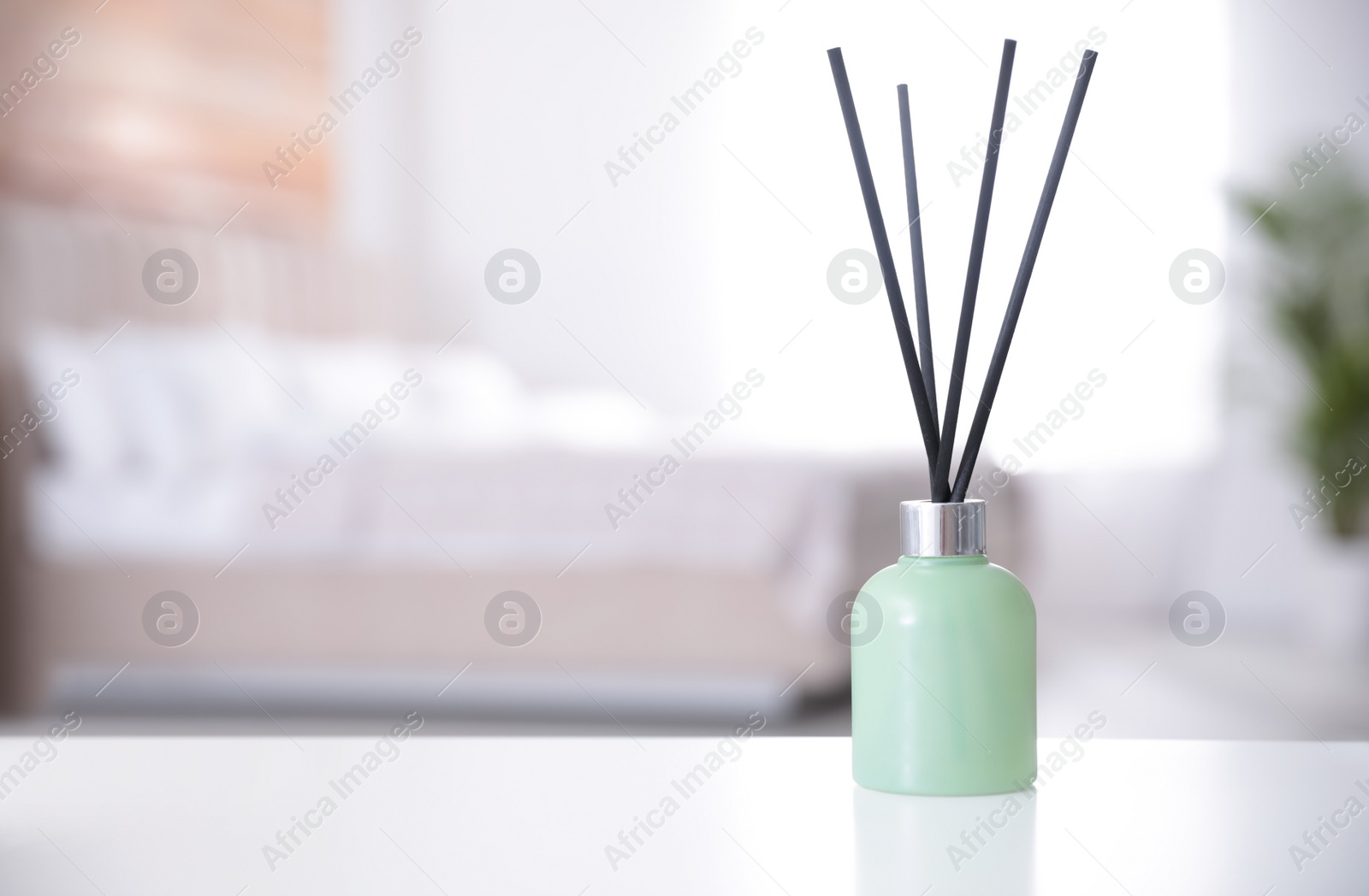 Photo of Reed air freshener on white table indoors. Space for text