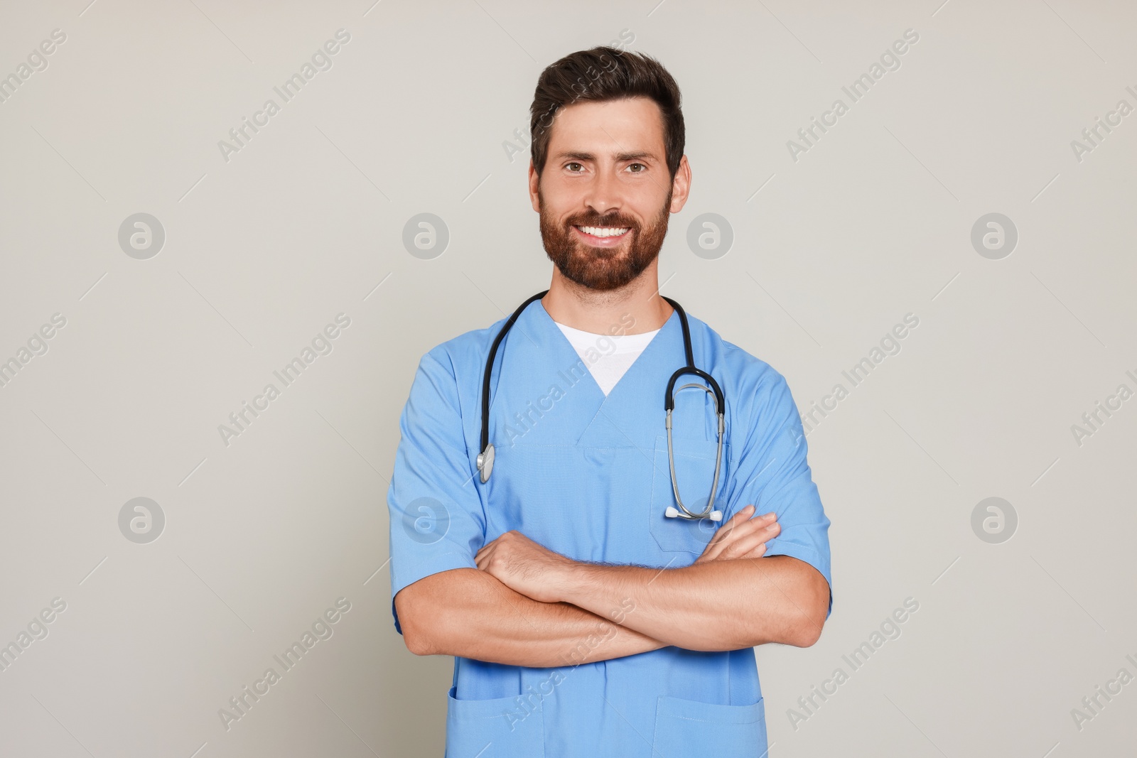 Photo of Happy doctor with stethoscope on light grey background