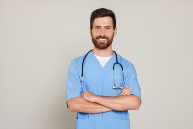 Photo of Happy doctor with stethoscope on light grey background