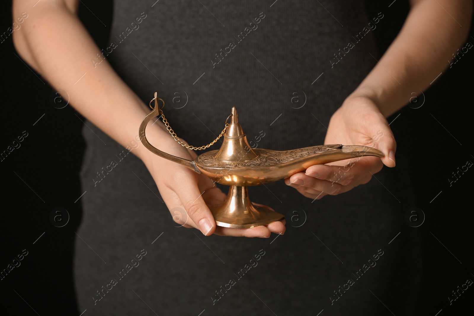 Photo of Woman rubbing magical Aladdin lamp, closeup