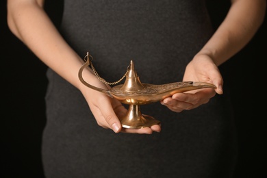 Photo of Woman rubbing magical Aladdin lamp, closeup