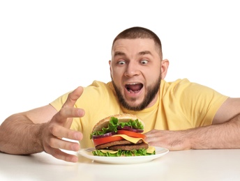 Young hungry man and tasty burger on white background