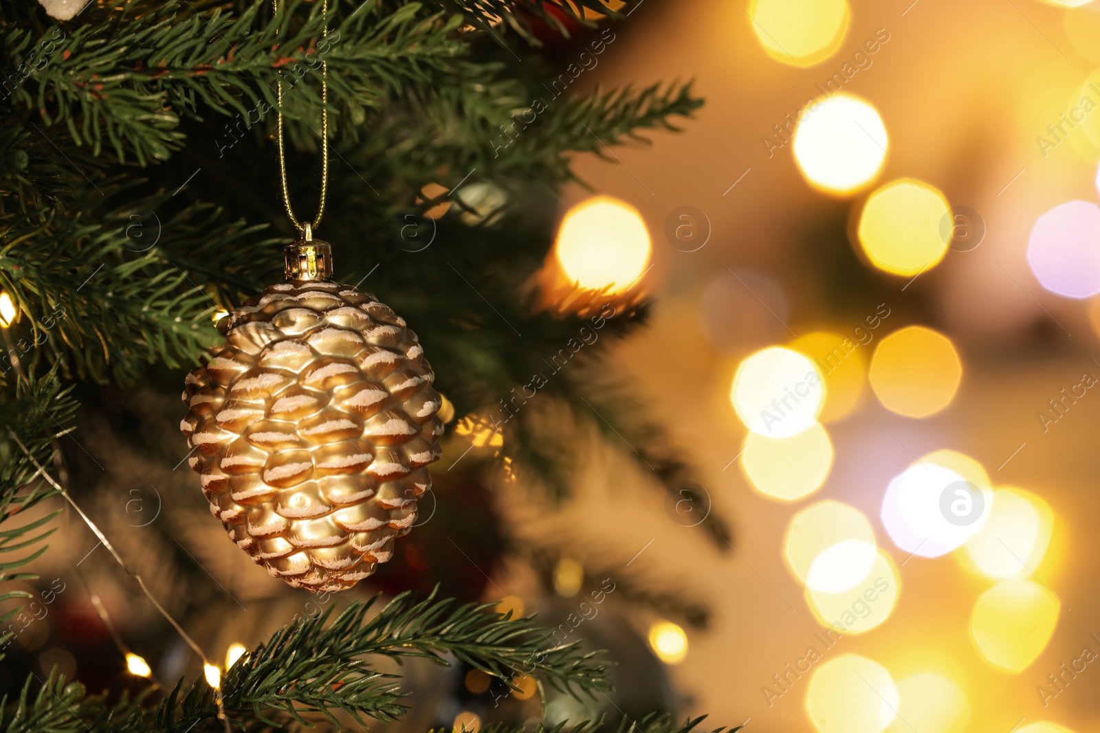 Photo of Beautiful shiny holiday bauble hanging on Christmas tree against blurred fairy lights, closeup. Space for text