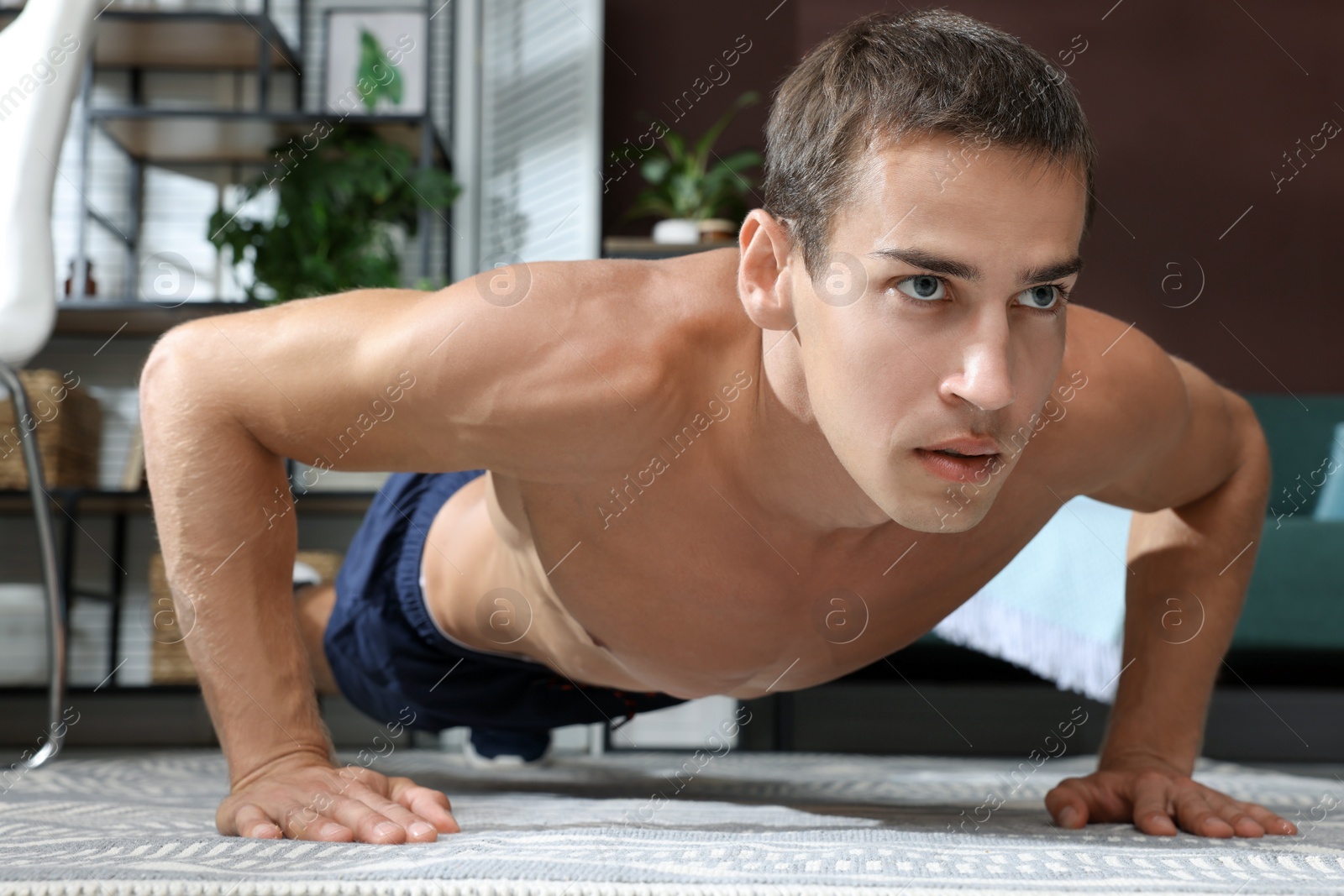 Photo of Handsome man doing plank exercise on floor at home