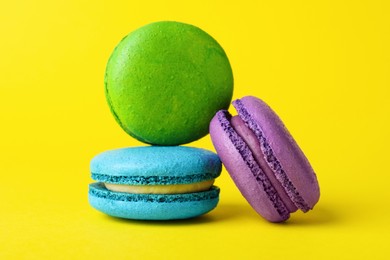Photo of Delicious colorful macarons on yellow background, closeup