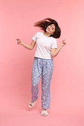 Happy woman in pyjama shaking head on pink background