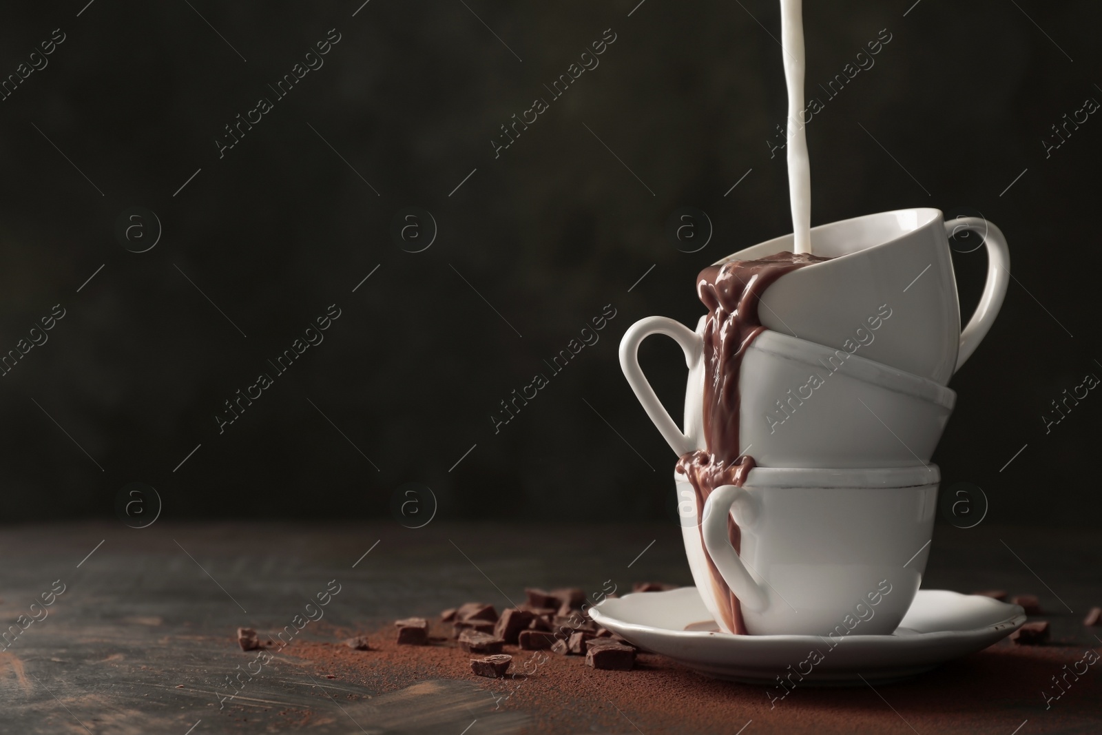 Photo of Adding milk to tasty hot chocolate on table. Space for text