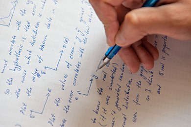 Student writing mathematical calculations on paper, closeup