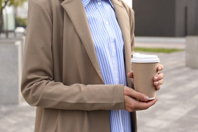 Coffee to go. Woman with paper cup of drink outdoors, closeup