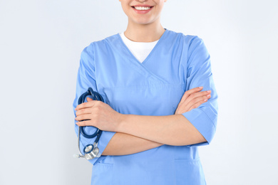 Photo of Young doctor with stethoscope on light background, closeup