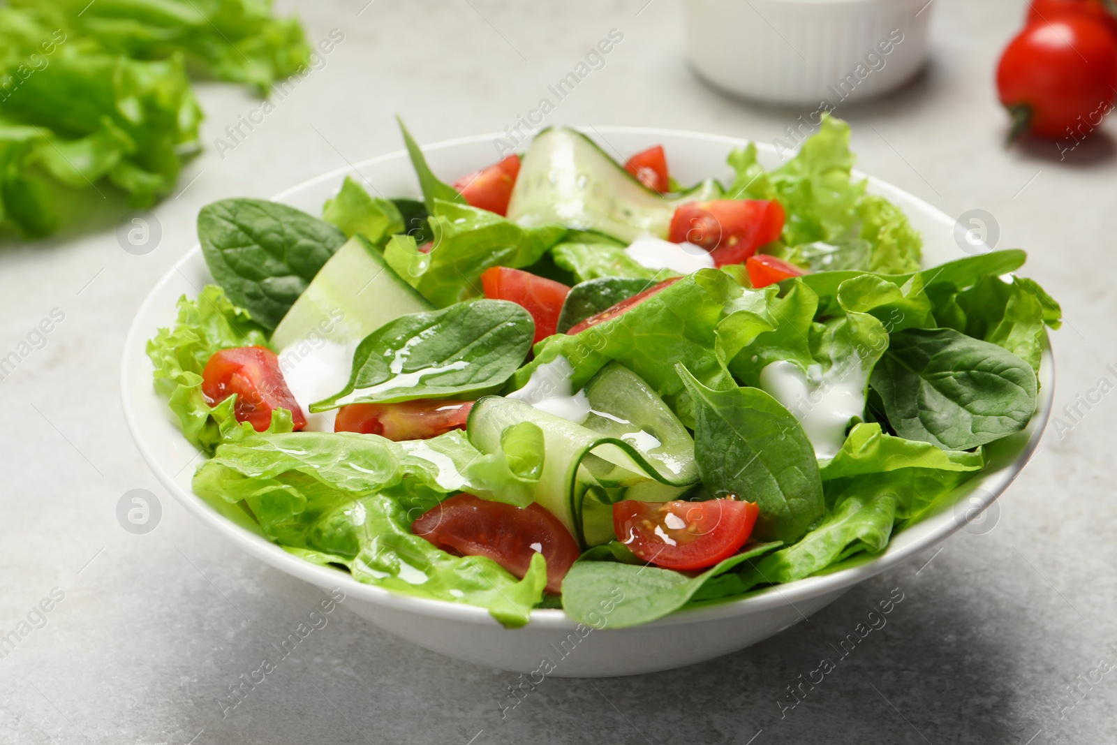 Photo of Delicious vegetable salad on light grey table, closeup