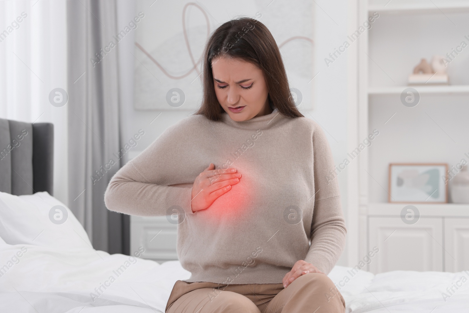 Image of Young woman suffering from breast pain on bed at home
