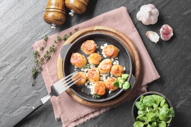 Delicious fried scallops in dish served on dark gray textured table, flat lay