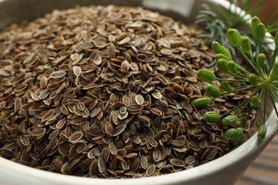 Photo of Bowl of dry seeds and fresh dill, closeup
