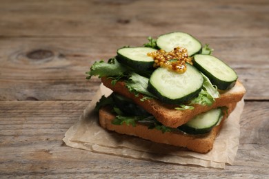 Photo of Tasty cucumber sandwiches with arugula and mustard on wooden table