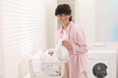 Happy woman with laundry near window indoors