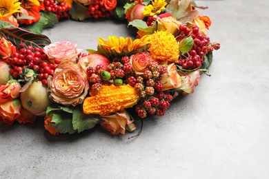 Photo of Beautiful autumnal wreath with flowers, berries and fruits on light grey background, closeup