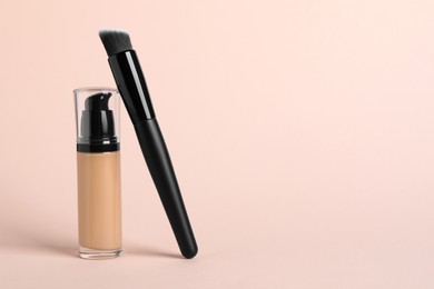 Bottle of skin foundation and brush on beige background, space for text. Makeup product