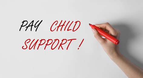 Image of Woman writing phrase PAY CHILD SUPPORT! on white background, closeup