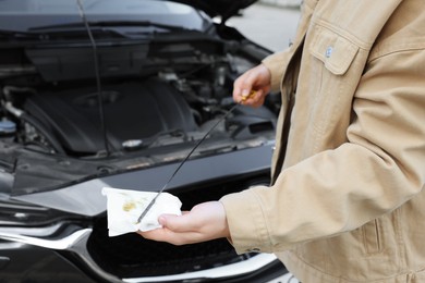 Photo of Man checking motor oil level in car with dipstick, closeup